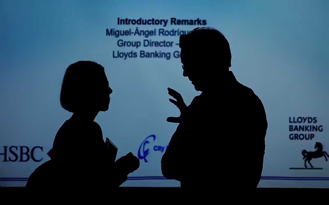 Photography case studies: two business delegates in conversation at a corporate conference, photographed in silhouette against a presentation screen.
